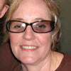 A person wearing glasses smiling at the camera.